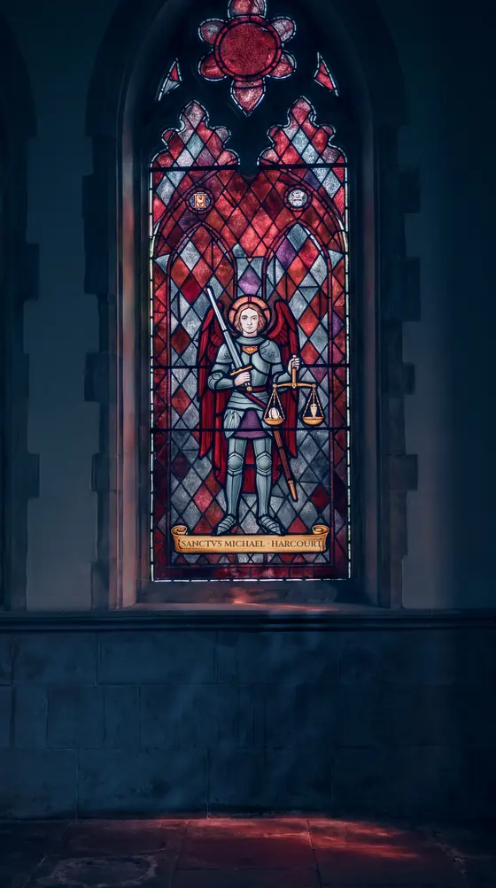 A stained-glass saint in armour holding a pair of scales